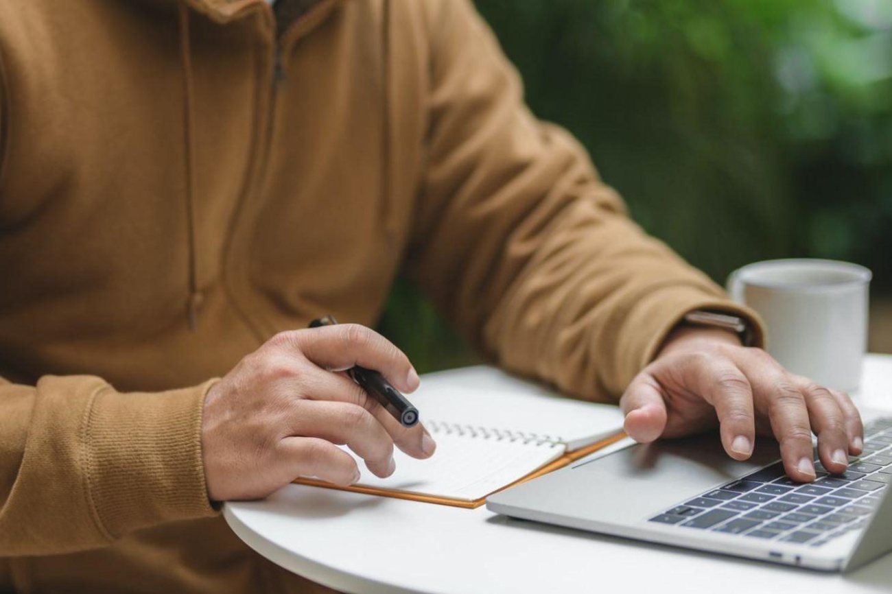 Man planning out finances on computer and notebook 3